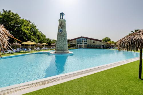 - une piscine avec un phare à côté d'un bâtiment dans l'établissement Camping Domaine Les Carrelets de Soulac - Maeva Sélection, à Soulac-sur-Mer