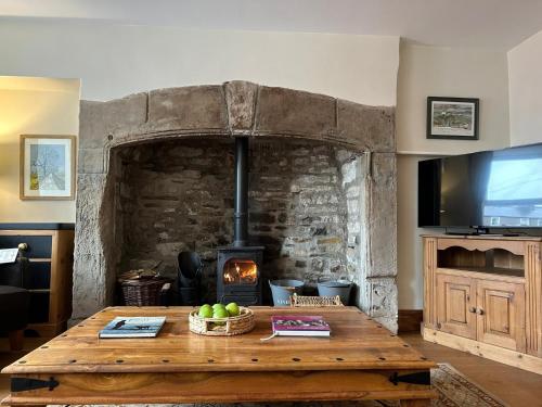 a living room with a wooden table and a fireplace at Heart Of Hawes Holiday Cottage in Hawes