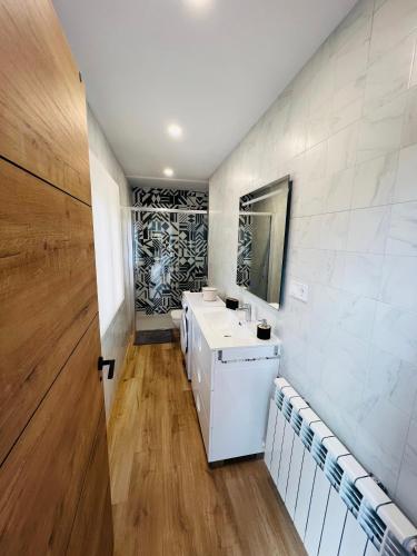 bagno con lavandino bianco e specchio di A CASA DO LUGAR a Sampaio