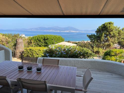 une table et des chaises en bois avec vue sur l'océan dans l'établissement Villa Sampiero, sur mer, piscine et plage à pieds, à Pietrosella