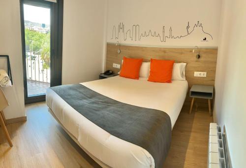 1 dormitorio con 1 cama grande con almohadas de color naranja en Hostal Sans, en Barcelona