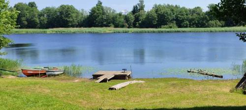 un muelle a orillas de un lago con dos barcos en Pie Ventas, en Ventspils