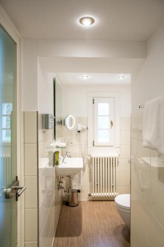 a white bathroom with a sink and a toilet at Hotel Hofgut Sternen - Ravennaschlucht in Breitnau