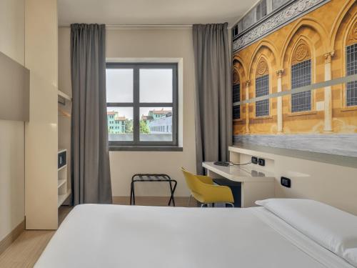 una camera con letto, scrivania e finestra di B&B Hotel Cremona a Cremona