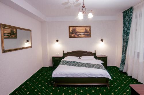 a bedroom with a bed and a green carpet at Hotel Transalpin in Obarsia-Lotrului
