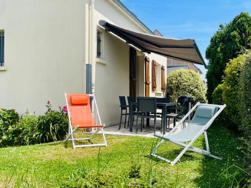 2 chaises et une table dans la cour dans l'établissement Le DÉRIVEUR - Maison familiale rénovée 3 chambres - Jardin et terrasse, à Saint-Lunaire