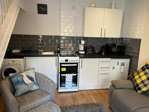 a kitchen with white cabinets and an open oven at Seagull Cottage in Looe