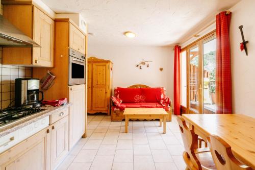 une cuisine avec une table et un canapé rouge. dans l'établissement Gentiane, à Valloire