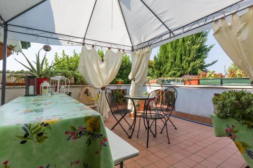 a patio with a table and chairs and a white canopy at Au Jardin fleuri in San Giovanni Lupatoto