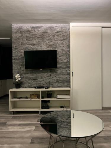a living room with a television on a brick wall at Apartman OMAR stan na dan besplatan parking Sarajevo in Sarajevo