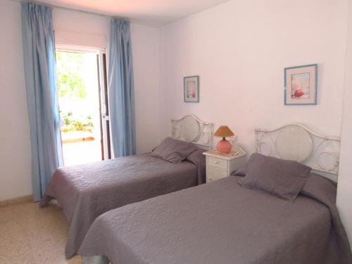 1 dormitorio con 2 camas y una ventana con puerta en Pueblo Mar - Guadalmar en Málaga