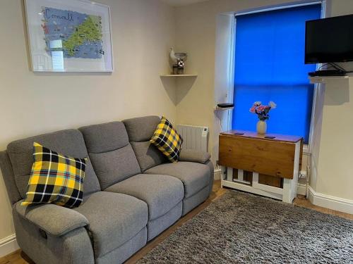 a living room with a gray couch and a blue window at Seagull Cottage in Looe