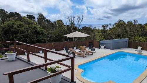 una piscina su un patio con sedie e ombrellone di Villa Capelinhos a Capelo