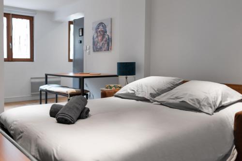 - un lit blanc avec des oreillers et une table dans la chambre dans l'établissement Le Gorille hypercentre et climatisation, à Toulouse