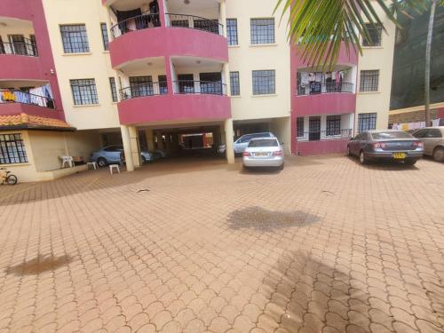 a parking lot in front of a pink building at Kaimbu Road Zone Apartments in Kiambu