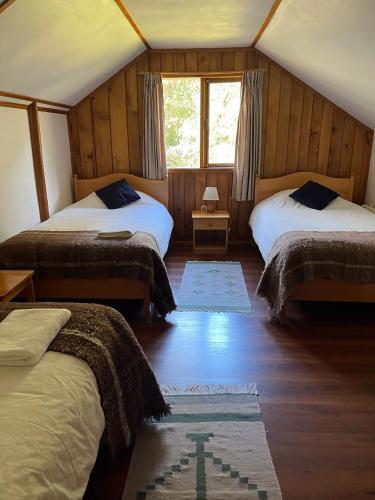 a bedroom with two beds and a window at El Pangue Lodge in Puerto Puyuhuapi