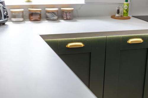 a kitchen with green cabinets and a white counter top at FLOUR MILL HOUSE at PITKERRO MILL, 4 double bedrooms, TVs, 3 en-suite, separate shower, wc, fully equipped kitchen, games room, large family lounge, private parking, WiFi, private garden and courtyard, long stay rates available through Honeycomb Hosts in Dundee