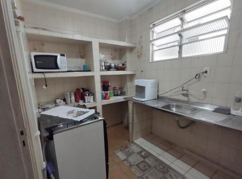 a small kitchen with a sink and a microwave at Condominio Ed Verde Oliva in São Vicente
