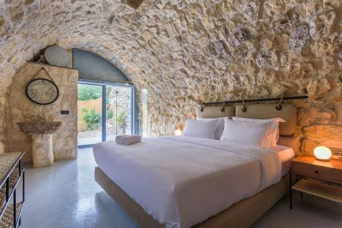 a bedroom with a large bed in a stone wall at Amani Luxury 4-Bedroom Villa & Pool in Batroun in Batroûn