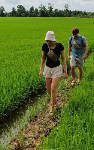two people walking through a field of grass at AUTHENTIC HOMESTAY in Can Tho