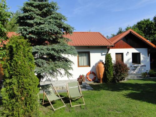 a house with two lawn chairs in the yard at Domki Zielona Osada in Szczenurze
