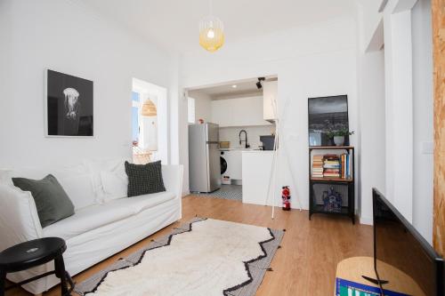 a living room with a white couch and a kitchen at Alba Beach Boutique Apartment in Estoril