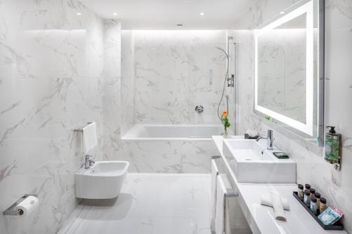 Baño blanco con bañera y lavamanos en Starhotels Majestic en Turín