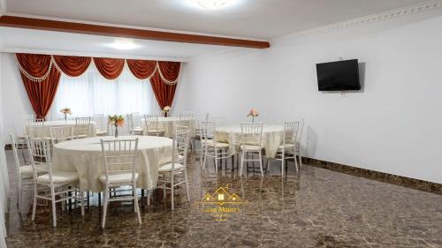 a room with white tables and chairs and a flat screen tv at Casa Munty in Orlat