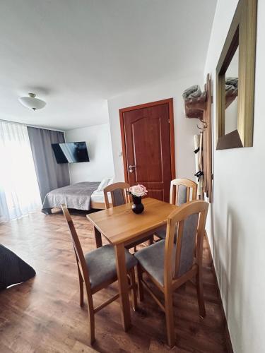 a dining room with a table and chairs and a bedroom at Willa Ada Pokoje & Apartamenty in Karwia