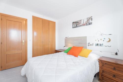 Un dormitorio con una cama blanca con almohadas coloridas. en Apartamento playa Canet, en Canet de Berenguer