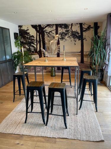 une table de salle à manger avec quatre tabourets sur un tapis dans l'établissement Maison 8 personnes avec piscine, à Labenne