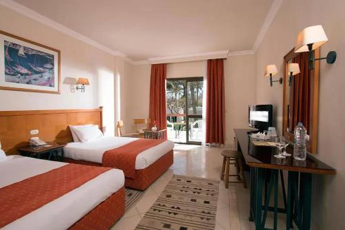 Cette chambre comprend deux lits et un bureau. dans l'établissement ZYA Regina Resort and Aqua Park Hurghada, à Hurghada