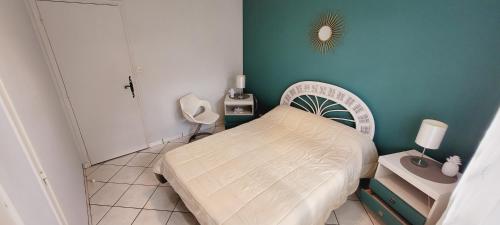 - une petite chambre avec un lit et un mur bleu dans l'établissement Les Roitelets, à Mimizan-Plage