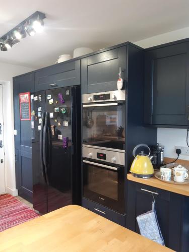 a kitchen with black cabinets and a black refrigerator at Marlow in Swanage