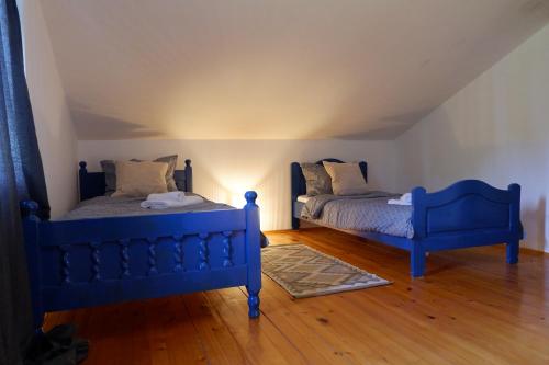 twee blauwe bedden in een kamer met houten vloeren bij Bosnian Mountain Retreat in Prijedor