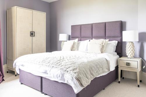 a bedroom with a large bed with a purple headboard at South Lodge, St Osyth Priory in Saint Osyth