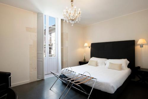 1 dormitorio con 1 cama blanca grande con lámpara de araña en Hotel Palazzo Cavalieri, en Siracusa
