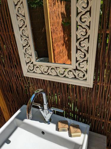 a sink in a bathroom with a mirror above it at Glamping Grindhuset in Helgeroa