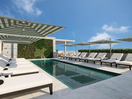 a swimming pool with lounge chairs and umbrellas at Arlo Washington DC in Washington