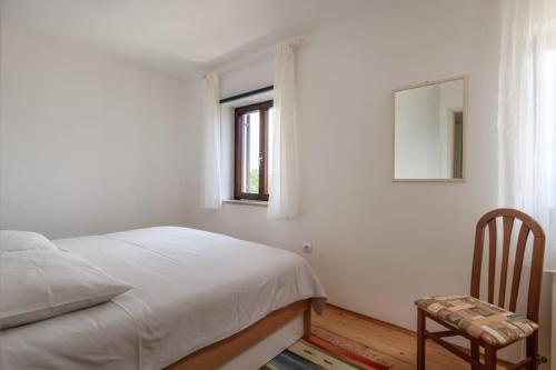 a bedroom with a bed and a window and a chair at Yasmin in Brseč