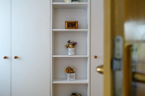 a white book shelf with two potted plants on it at Yasmin in Brseč