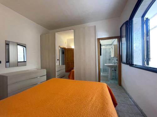 1 dormitorio con cama de color naranja y baño en Villa Ciccarese dentro la spiaggia, en Porto Cesareo