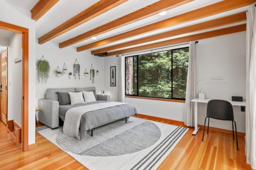 a bedroom with a bed and a desk and a window at Redwood Oasis - Eco-luxury cabin with hot tub in the Santa Cruz Mountains in Ben Lomond