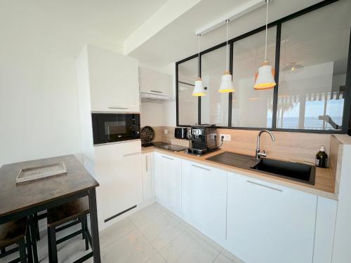 une cuisine avec des armoires blanches et un évier dans l'établissement Ravissant T1 au bord de l'eau Juan Les Pins, à Antibes