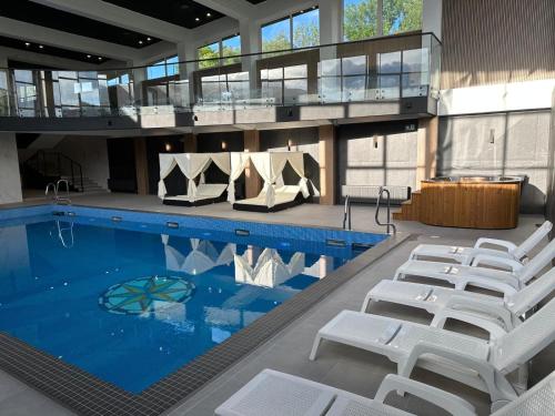 a large swimming pool with white chairs and tables at WRZOS resort & wellness in Węgierska Górka