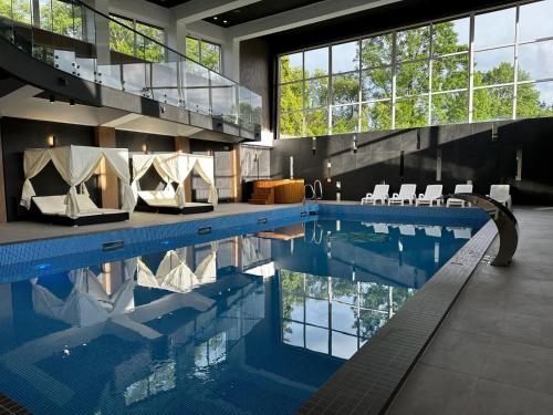 a large swimming pool with chairs and a large window at WRZOS resort & wellness in Węgierska Górka