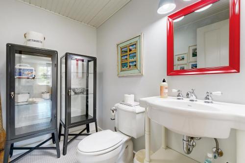 a bathroom with a toilet and a sink and a mirror at Blissful Island Haven in Oak Bluffs