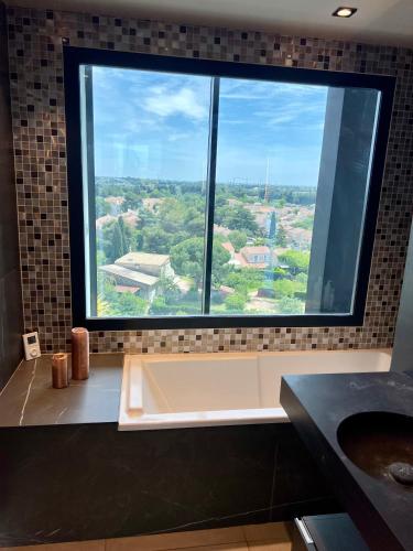 La salle de bains est pourvue d'une grande fenêtre et d'une baignoire. dans l'établissement Luxueux et unique Penthouse en Rooftop à Montpellier, à Montpellier