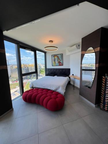 une chambre avec un pouf rouge devant un lit dans l'établissement Luxueux et unique Penthouse en Rooftop à Montpellier, à Montpellier