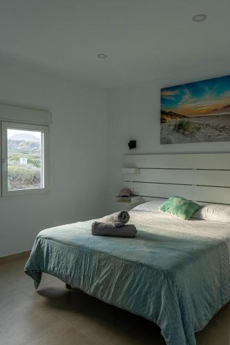 a white bedroom with a large bed with a window at Kiposhi Beach Apartments Punta Mujeres in Haría